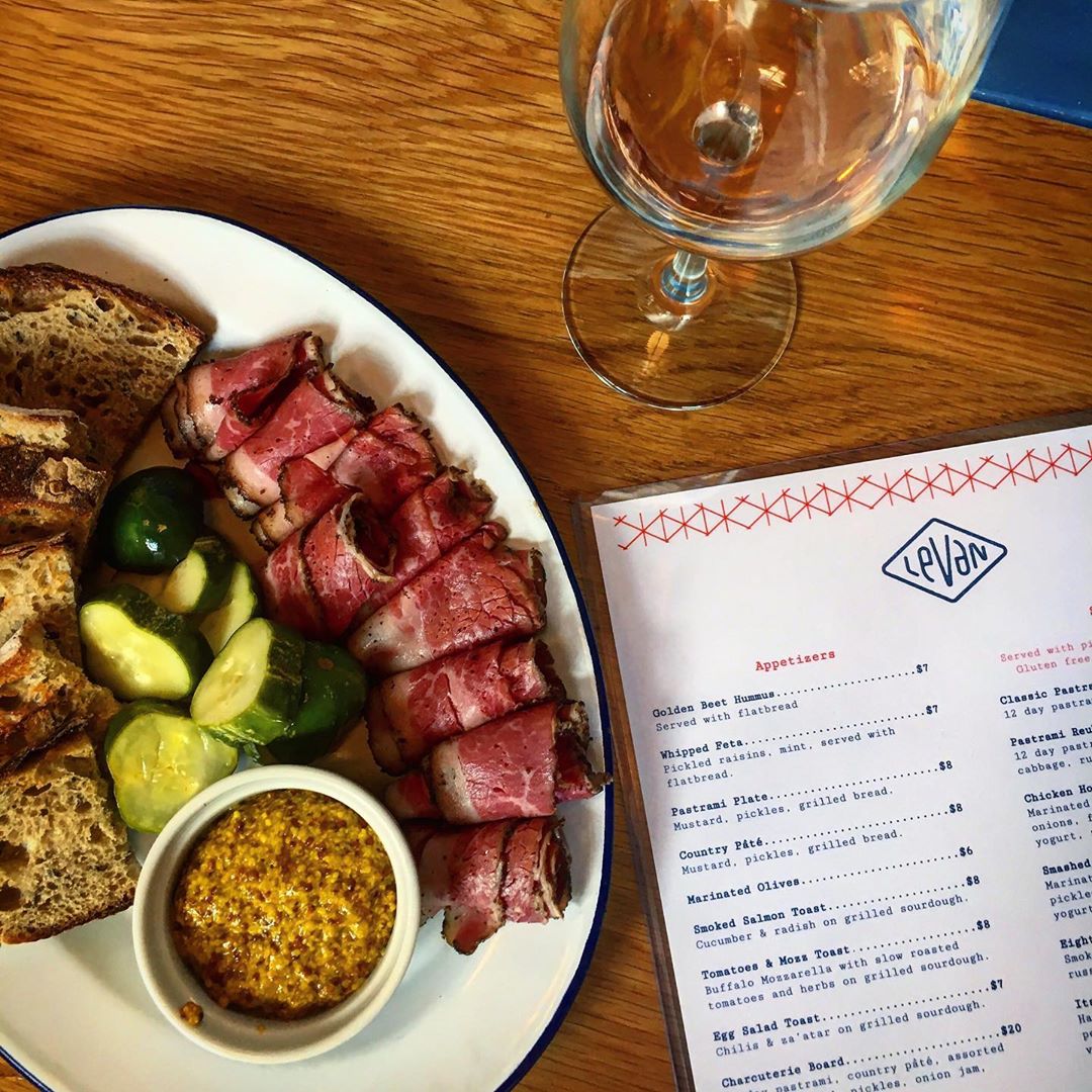 a Leven nosh board with pastrami, mustard, pickles, rye, and a perfectly paired wine