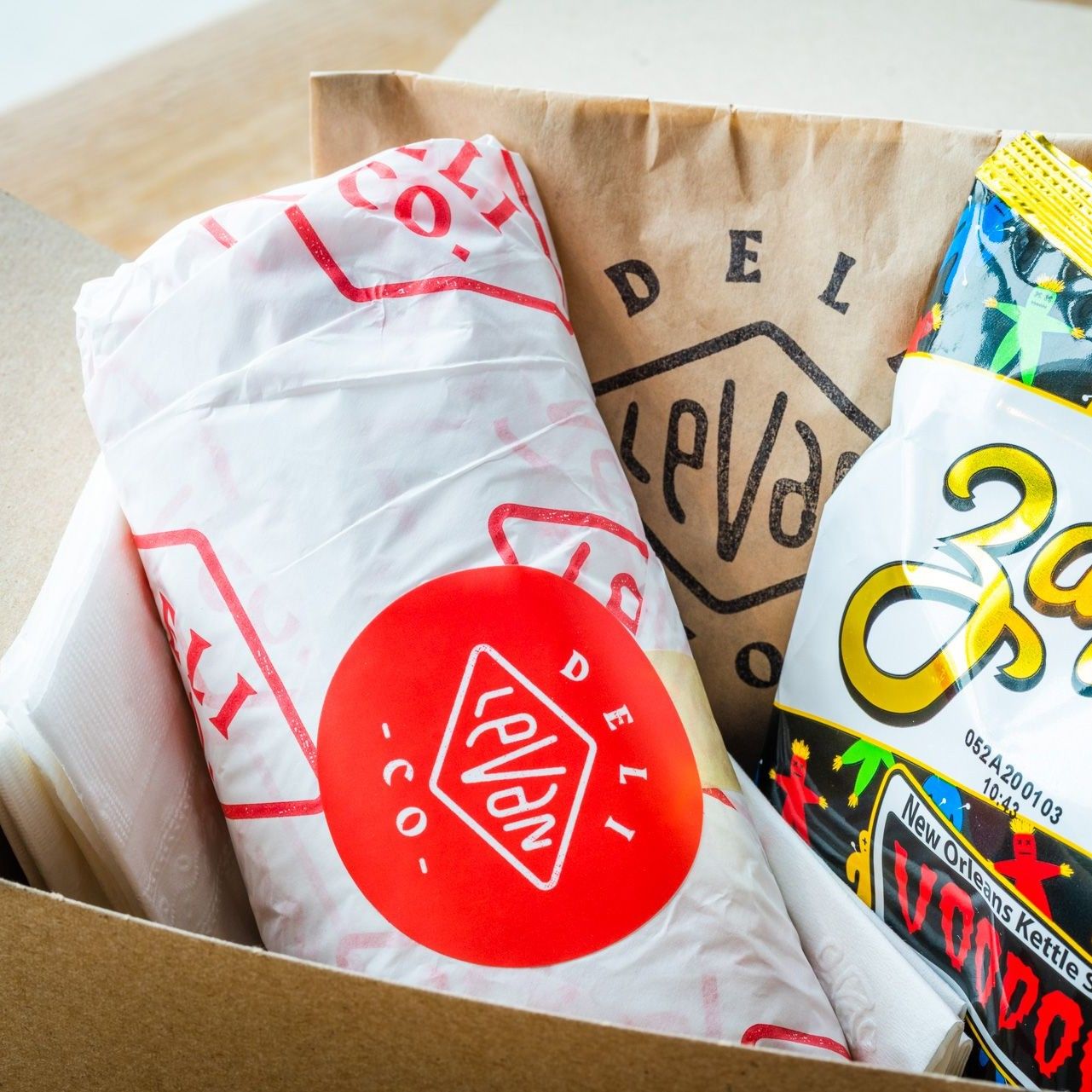 a catering box with sandwich, chips, and a cookie