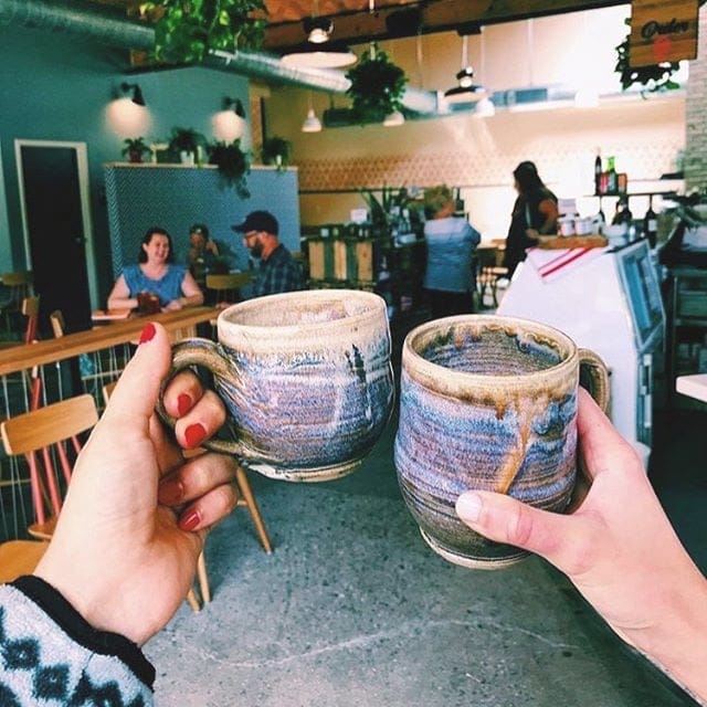 two people cheersing their coffee mugs